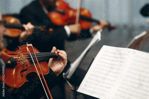 Elegant string quartet performing at wedding reception in restaurant, handsome man in suits playing violin and cello at theatre play orchestra close-up, music concept