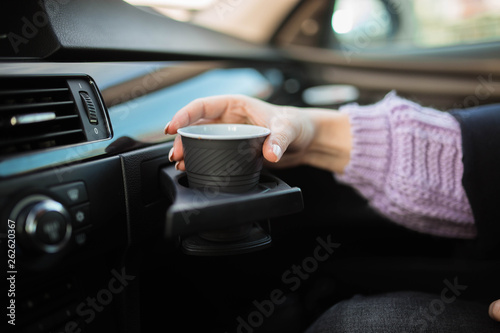 girl's hand with a plastic cup of coffee in the car. cup holder