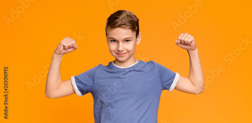 Smiling boy demonstrating his biceps and muscles