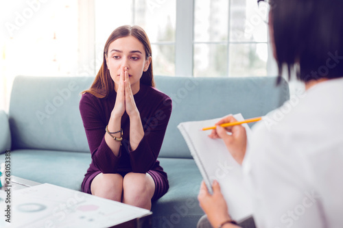 Professional psychologist carefully making notes during a treatment interview