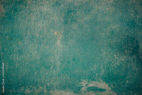 Old grunge weathered crumbled peeling green painted plastered house wall surface detail close up as background
