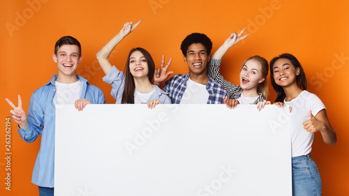 Happy friends holding empty banner, orange background