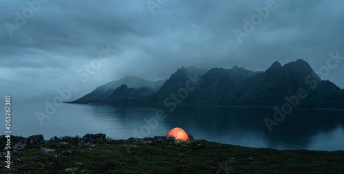 Illuminated tent at the lofoten islands on the rainy evening with copy space