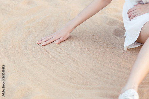 Girl sitting on the beach wipes the sand by hand