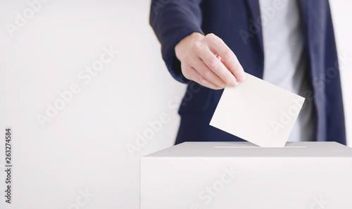 Voting. Man putting a ballot into a voting box.