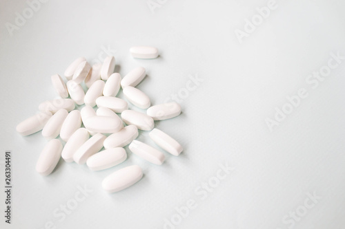 White oblong pills oral medication tablets on light background. Selective soft focus, text copy space. Health care, medicine pharmaceutical drugstore concept.