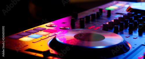 DJ controller colorful buttons live show at night club playing edm dance music in neon light
