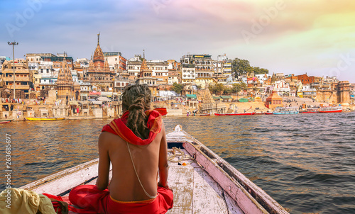 Varanasi city architecture with Ganges river bank at sunset with view of sadhu baba enjoying a boat ride on river Ganges.