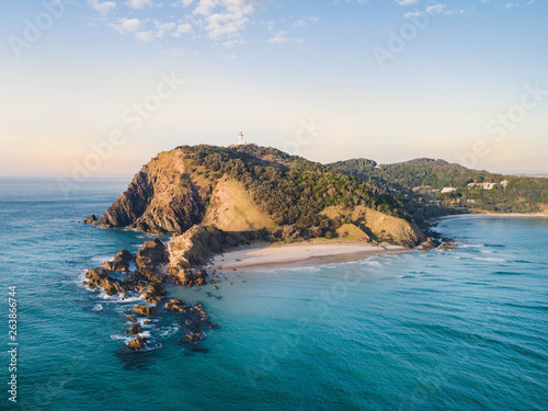 Aerial shot at sunrise over the ocean and white sand beach with swimmers and surfers enjoying summer