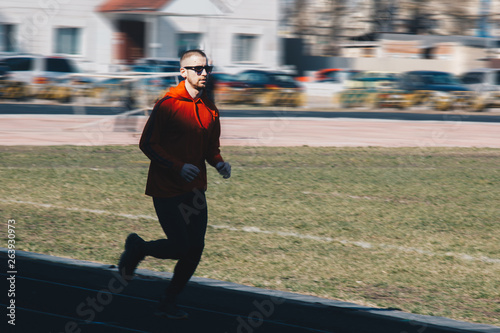 running man training outdoors with sunglasses. runner at the stadium on a sunny day. shot in motion