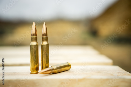 308 caliber ammunition for a rifle standing on a wooden table on the background of the shooting range