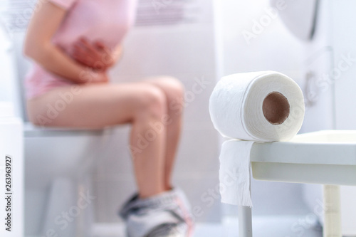 Ill, unwell woman suffering from diarrhea, constipation and cystitis at toilet. Stomach pain during PMS. Health care and pain concept