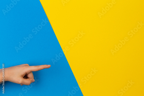Kid hands pointing to something on blue and yellow background