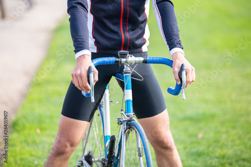Unrecognizable young fit male cyclist in sportswear sitting on bike in park