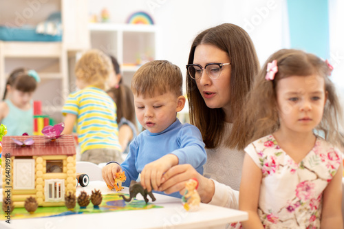 Group of kids playing with teacher in kindergarten