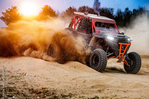 UTV buggy in the action on sand with sunshine