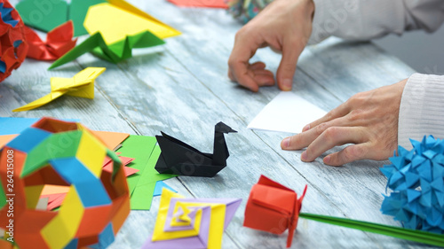 One origami paper swans. Close up. Male hands, origami master.