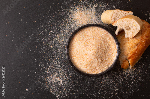 Food ingredients homemade organic bread crumbs in black ceramic bowl on black slate board