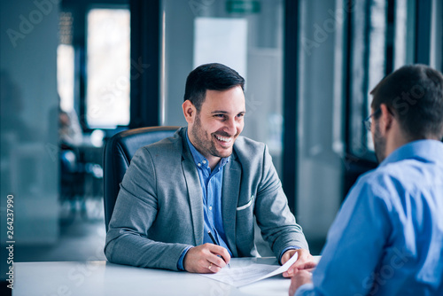 Handsome male client signing document on a meeting with real estate agent.