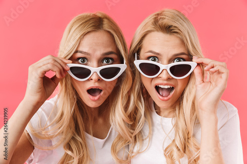 Shocked blonde twins take off sunglasses and looking at camera