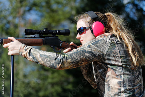 A woman aiming a rifle.