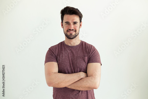 Handsome young man smiling and looking at camera over white background.