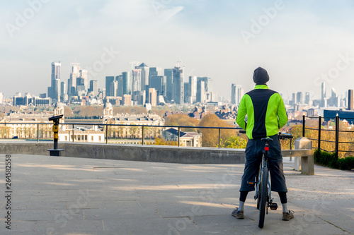 Man standing on bicycle look over city view in the morning.