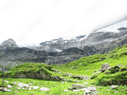 Green alpine meadows and grass against the snowy mountains of rocks and hills.