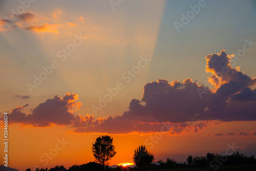 Orange morning sun rays illuminate the sky and the landscape in rural Balkans.