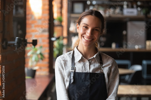 Happy mixed race female in apron smiling looking at camera