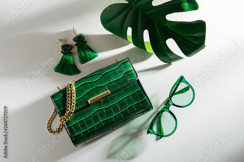 Feminine accessories collage with handbag, sunglasses and tropical leaf. Flat lay, top view. Summer fashion concept