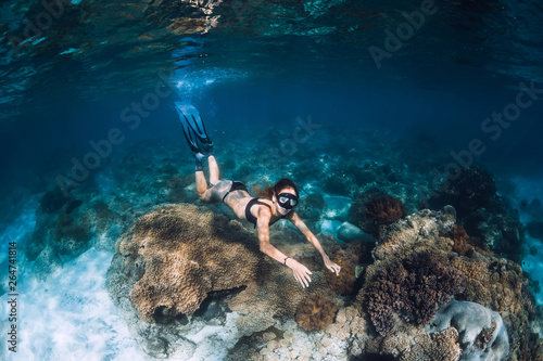 Woman freediver with fins and corals. Freediving underwater in blue ocean