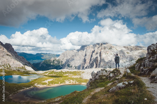 Fotograf turysta stoi na skale nad górskimi jeziorami Tre Cime di Lavaredo w słoneczny dzień