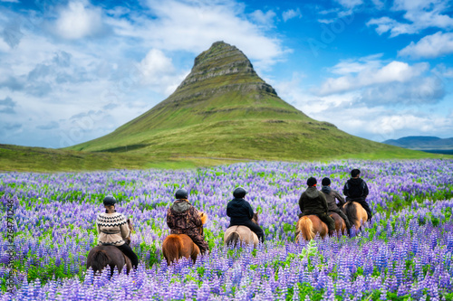 Tourist ride horse at Kirkjufell mountain landscape and waterfall in Iceland summer. Kirjufell is the beautiful landmark and the most photographed destination which attracts people to visit Iceland.