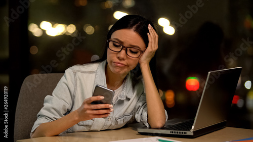 Lazy woman using cell phone at workplace, avoiding boring job, distraction
