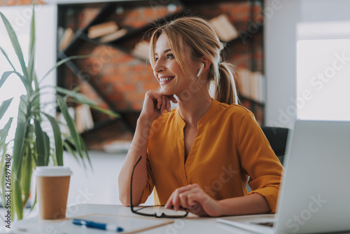 Cheerful woman wearing wireless earphones and smiling