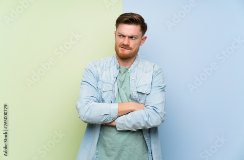 Redhead man over colorful background with confuse face expression