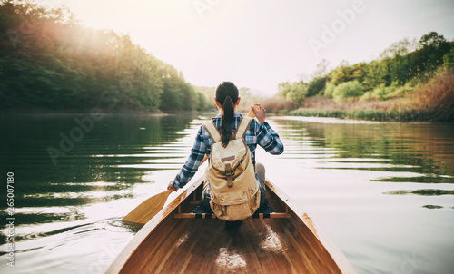 Rear view of travel woman rowing the boat at sunset