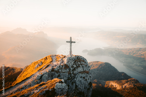 Mountain summit cross on alpine peak at sunset