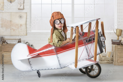 Little boy in the guise of a pilot at the helm of a toy-airplane