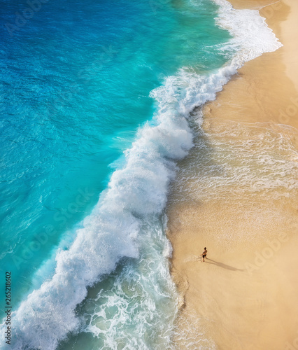 View of a man on the beach on Bali, Indonesia. Vacation and adventure. Top view from drone at beach, azure sea and relax man. Travel and relax - image