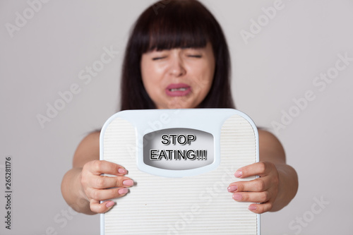 Sad woman with floor scales in her hands. Obesity and overweight. Diet and fitness. Healthy lifestyle and balanced diet. Selective fokus. 