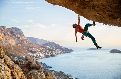 Caucasian man climbing challenging route in cave at sunset
