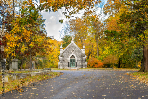 Small mausoleum at Sleepy Hollow Cemetery, surrounded by autumnal fall foliage, Upstate New York, NY, USA