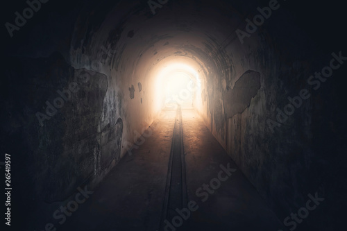 Light in end of tunnel. Long underground concrete corridor in abandoned bunker, toned
