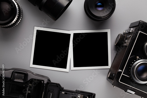 Photographic template - paper photo frames with blank space, lens and camera on gray table