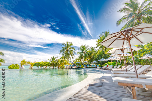 Luxury swimming pool in the tropical hotel or resort. Palm trees and infinity pool close to lounge chairs and umbrellas. Exotic travel destination, summer mood, beach holiday