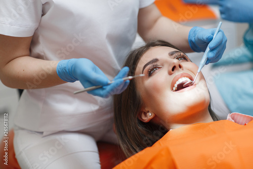 Dental clinic. Reception, examination of the patient. Teeth care. Young woman undergoes a dental examination by a dentist.Happy patient and dentist concept.Female dentist in dental office talking with