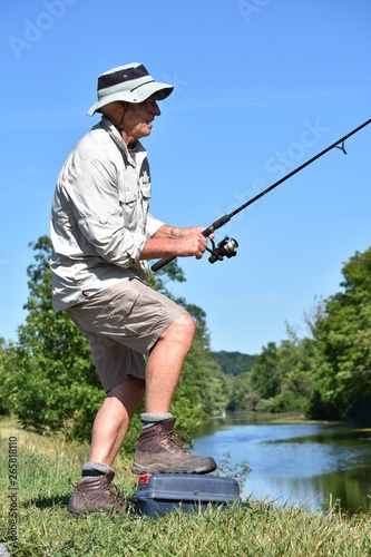 Retired Male Fisherman Standing With Rod And Reel Fishing