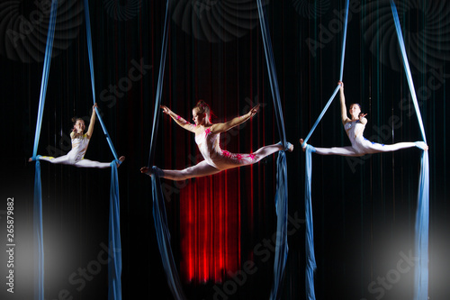 Circus actress acrobats performance on canvases. Team girls perform acrobatic elements in the air.